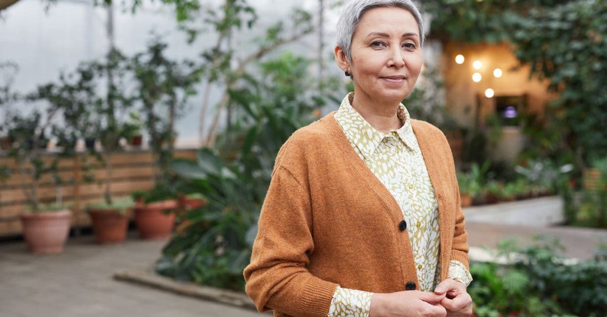 An older woman standing calmly in a garden