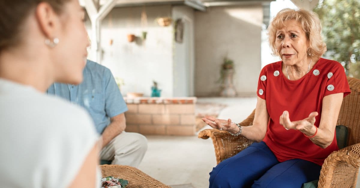 An adult child talking gently with their older parent at home